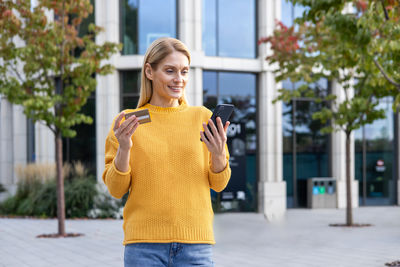 Portrait of young woman standing in city