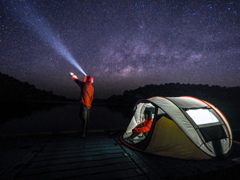 Man standing in illuminated field against sky at night