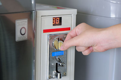 Cropped hand inserting coin in vending machine