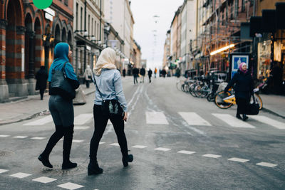 Full length rear view of young muslim women walking on street in city