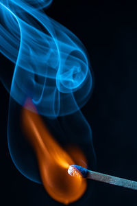 Close-up of lit candle against black background