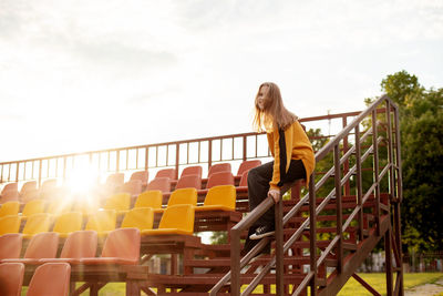 A teenage girl has fun and slides down the railing at the stadium