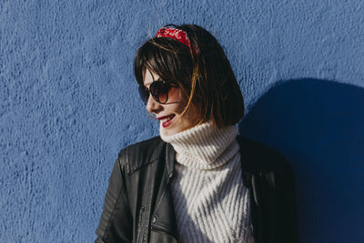 Portrait of smiling young woman against wall