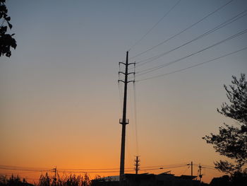 Low angle view of silhouette electricity pylon against sky during sunset