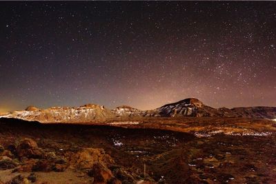 Scenic view of landscape against star field at night