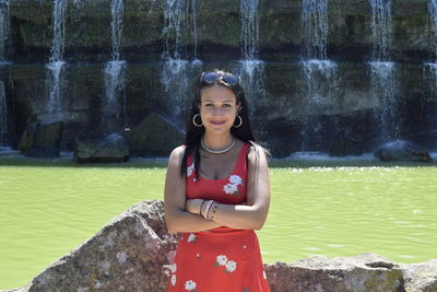 Portrait of beautiful woman wearing dress standing against fountain