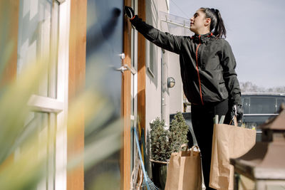 Delivery woman delivering groceries at entrance of house