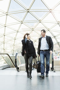 Business people talking while walking in front of escalator at railroad station