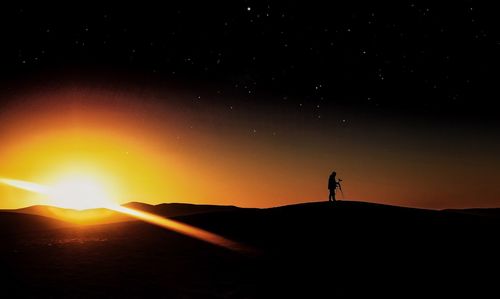 Silhouette man standing on field against sky at night