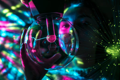 Digital composite image of woman and plasma ball with fiber optics