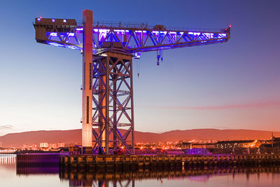 Illuminated commercial dock against sky during sunset