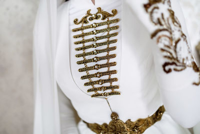 Gold metal decoration of the national caucasian wedding dress of a young girl on a light background