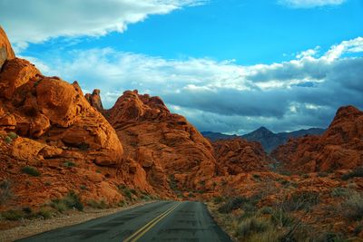 Road leading towards mountains against sky