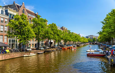 Boats moored in canal amidst buildings in city