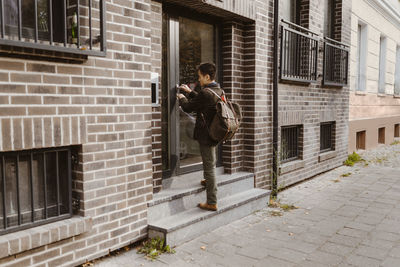 Man standing on steps while locking door of apartment