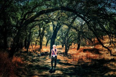 Rear view of man walking by trees in forest