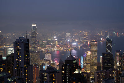 Illuminated buildings in city against sky at night