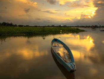 Boat in lake against sky during sunset