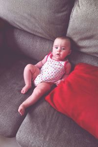 Portrait of baby girl lying on sofa at home