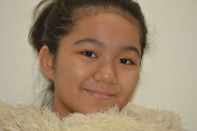 Portrait of a young girl holding a fluffy stuffed animal and smiling to the camera 