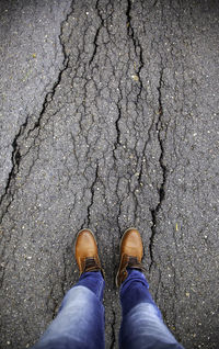 Low section of man standing on cracked street