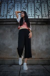 Full length portrait of woman standing against wall