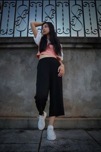 Full length portrait of woman standing against wall