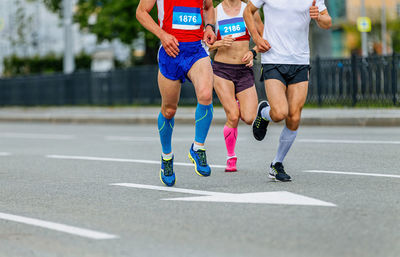 Two male and one female athletes in compression socks run city marathon