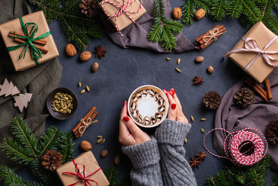 Cropped hands of woman holding coffee cup on table