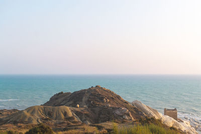 Rock formations by sea against clear sky