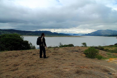 Rear view of friends standing on land against sky