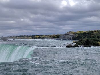 Scenic view of niagara falls against cloudy sky