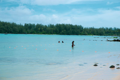 People in lake against sky