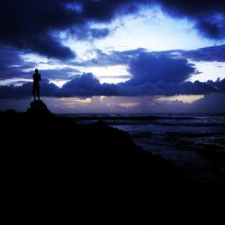 Silhouette of beach against cloudy sky