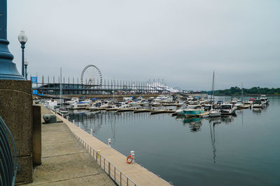 Boats moored at harbor against sky