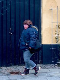 Side view of man standing against door