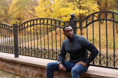 Portrait of young man sitting on railing