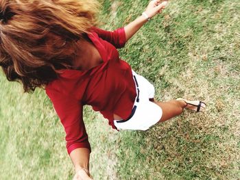 Low section of woman holding red ball on field