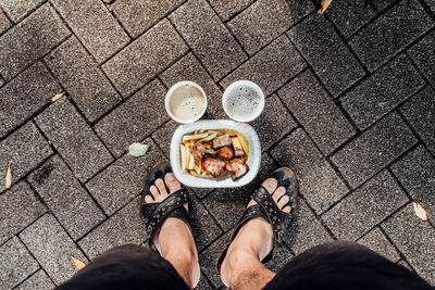 Low section of man standing by food of footpath