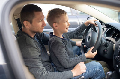 Man teaching car driving to son