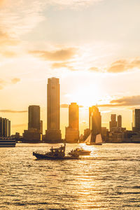 Sea by buildings against sky during sunset