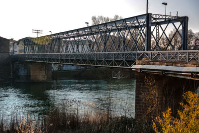 Bridge over river in city against sky