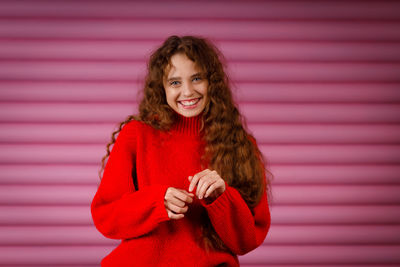 Portrait of young woman standing against wall