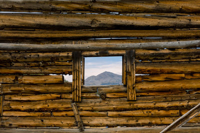 View of mountain peak seen through a rustic wooden window