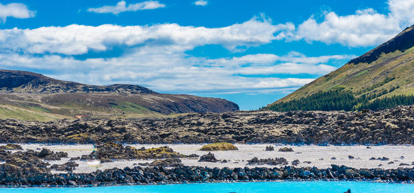 Scenic view of river by mountains against blue sky