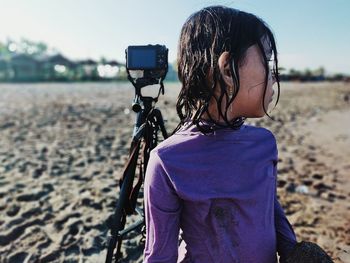 Rear view of woman photographing bicycle on sand