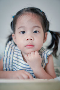 Portrait of cute girl lying on bed at home