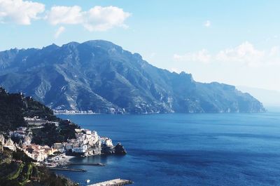 Scenic view of sea by townscape against sky