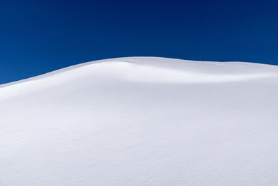 Snowcapped landscape against clear blue sky