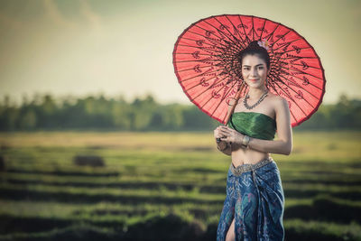 Woman with umbrella standing on field